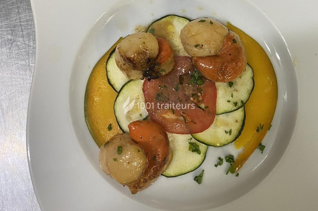 Assiette de noix de Saint-Jacques poêlées, disposées sur des tranches de courgettes, tomate et purée de légumes.