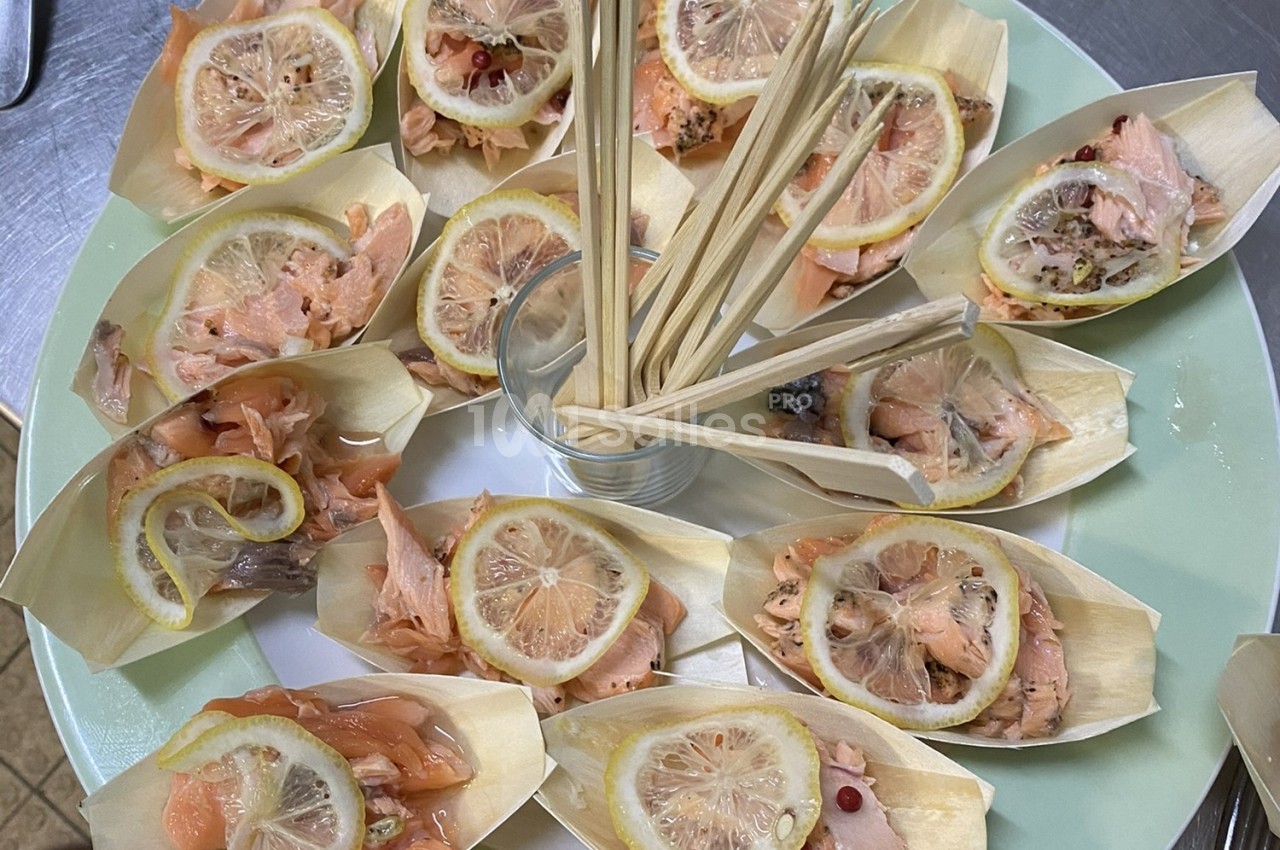 Assortiment de bouchées au saumon et citron présentées dans des coupelles en bois avec des piques en centre.