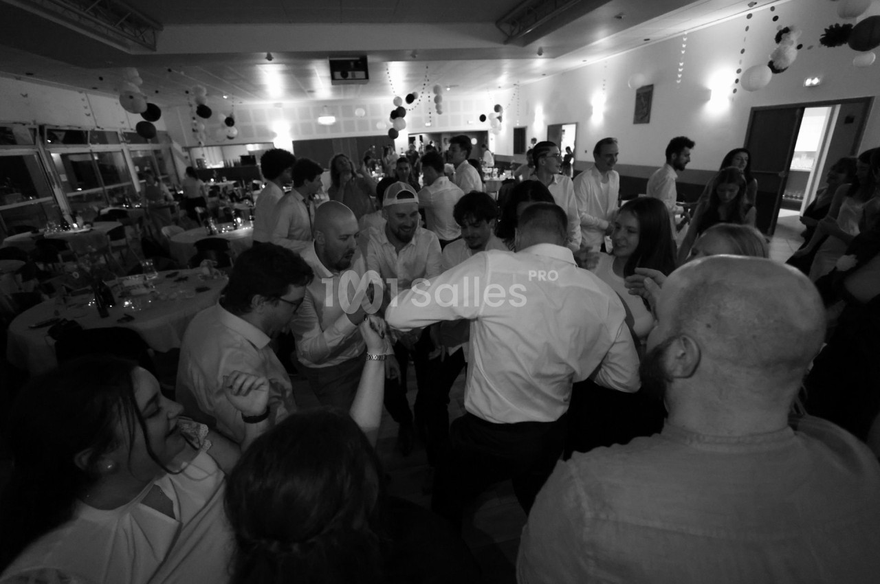 Groupe de personnes dansant et discutant dans une salle décorée lors d'un événement festif en intérieur.