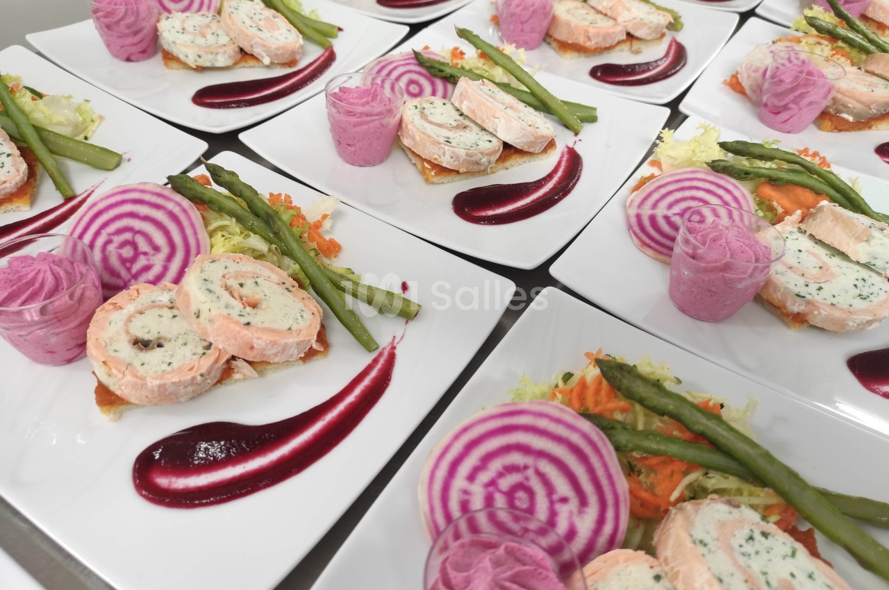 Assiettes dressées avec roulés de saumon, purée rose, betterave, asperges et sauce décorative rouge.