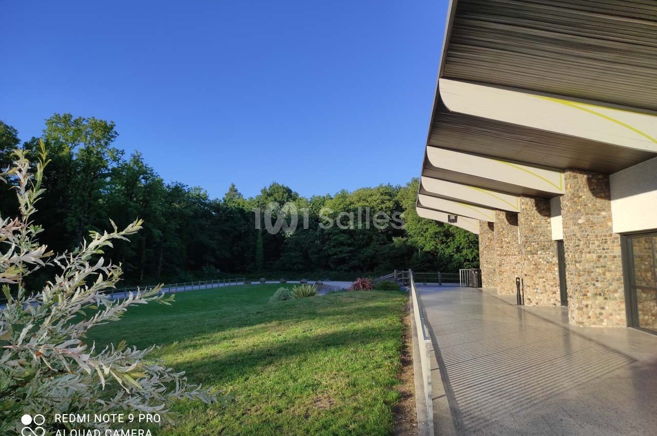 Bâtiment moderne avec façade en pierre, bordé d'une pelouse et d'arbres sous un ciel dégagé.