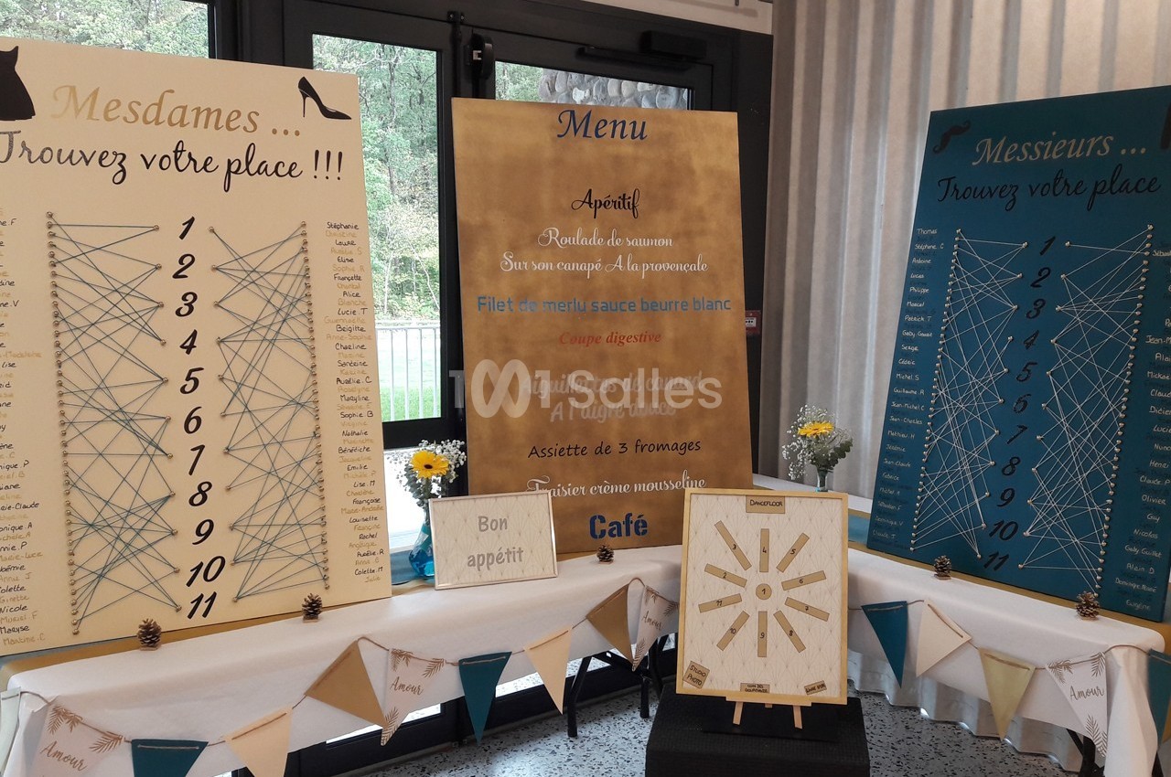 Panneaux de plan de table et menu d'un événement, décorés avec des fleurs et des guirlandes.