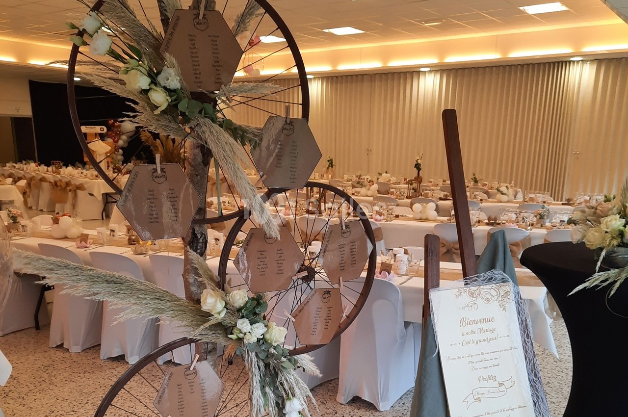 Décoration de mariage avec un plan de table sur des roues ornées de fleurs séchées, dans une salle de réception.