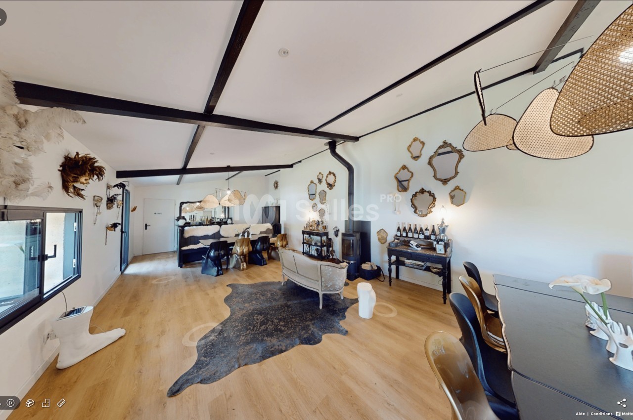 Espace intérieur lumineux avec parquet, mobilier éclectique, miroirs décoratifs et luminaires suspendus.