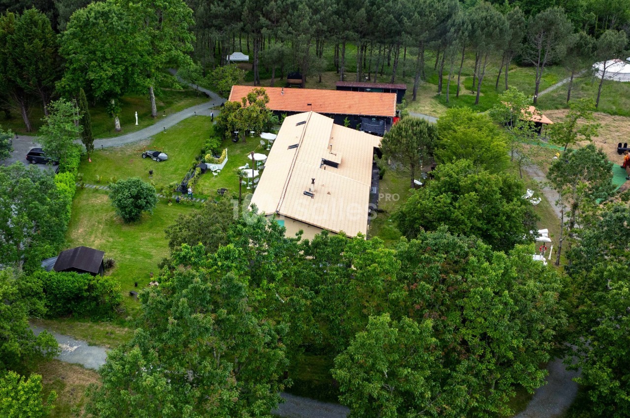 Vue aérienne d'un bâtiment avec toit orange entouré de verdure et d'arbres dans un cadre naturel.