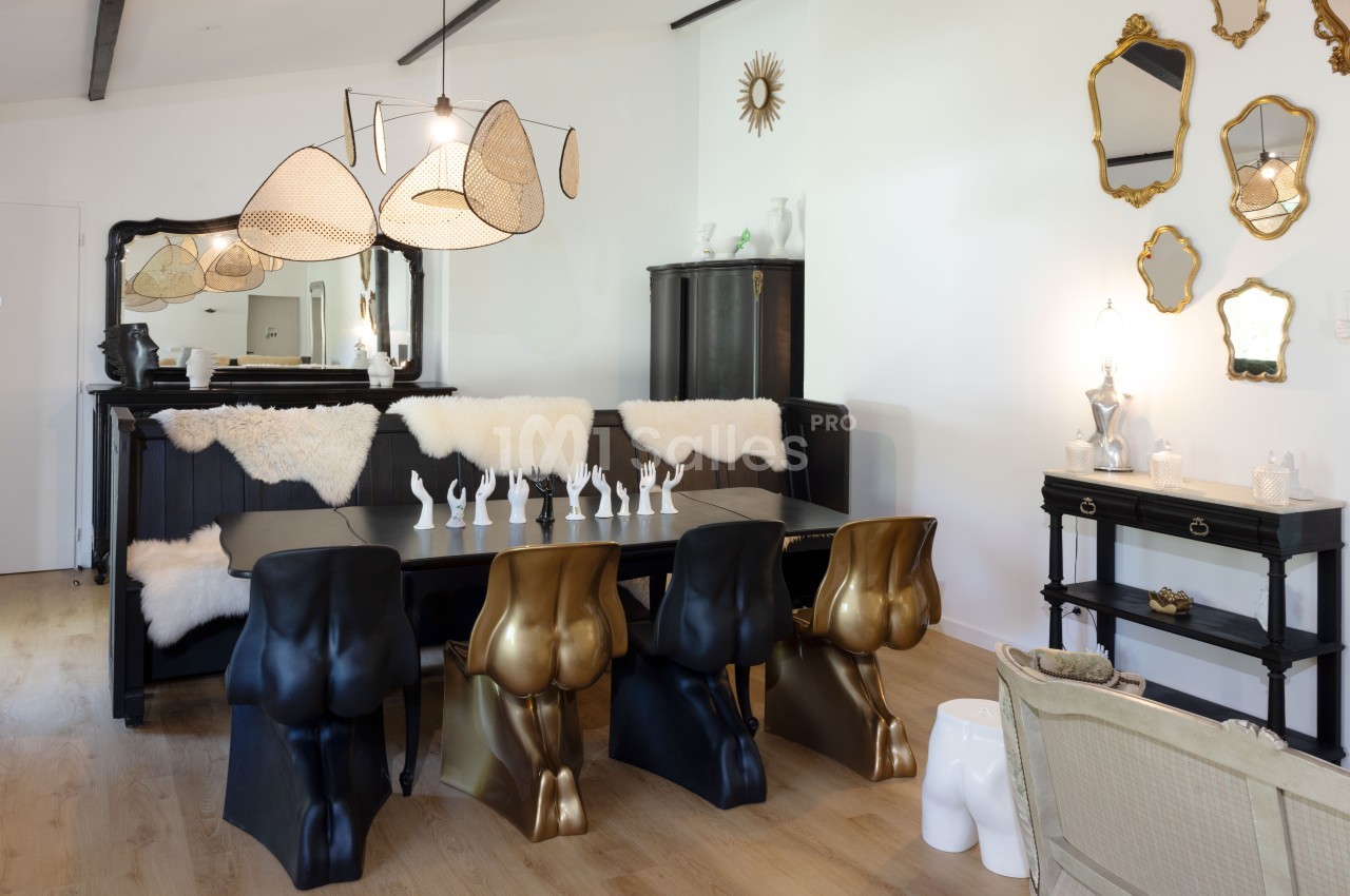 Salle à manger design avec chaises sculpturales, table noire, miroirs dorés et luminaires modernes dans un intérieur…
