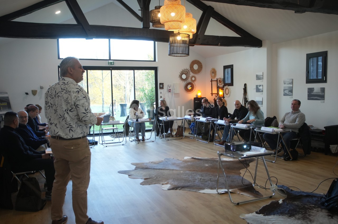 Un formateur s'adresse à un groupe de personnes assises dans une salle lumineuse avec des décorations murales.