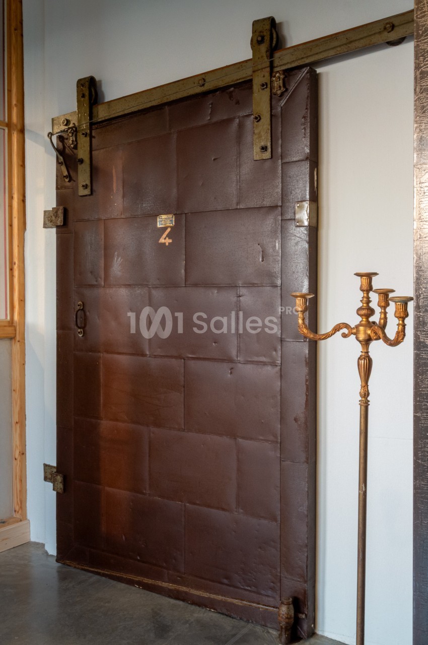 Porte coulissante en métal brun avec un mécanisme visible, située dans un intérieur au style industriel.