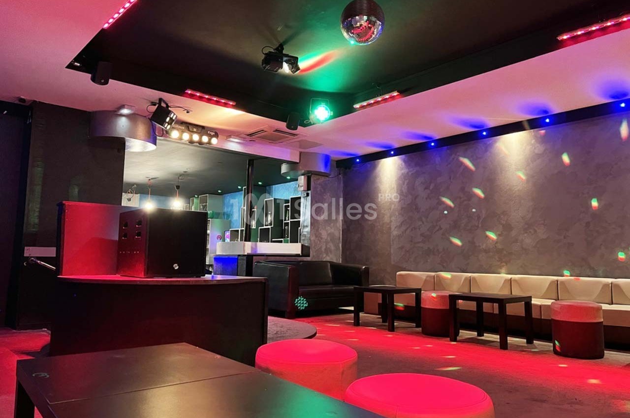 Salle de réception moderne avec éclairage coloré, banquettes en cuir clair et piste de danse équipée d'une boule disco.