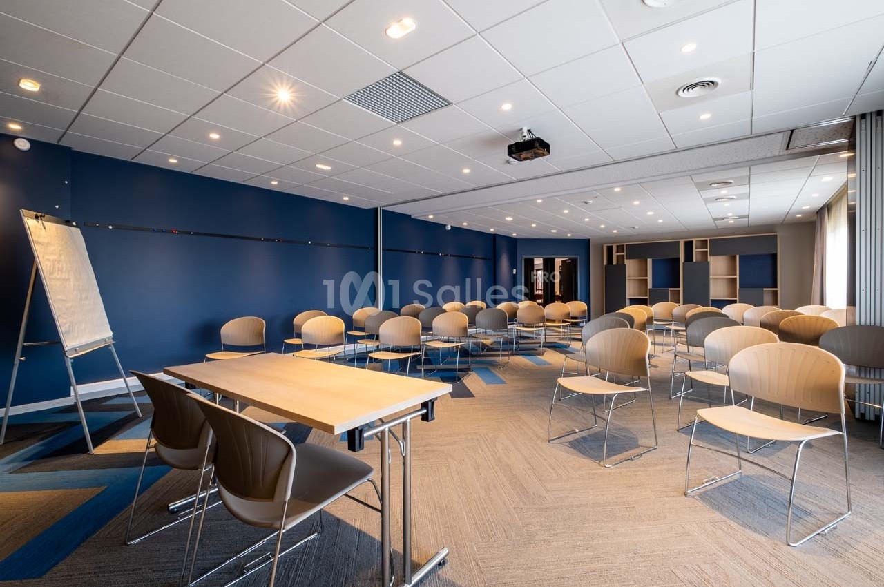 Salle de conférence moderne avec chaises alignées, tableau blanc et éclairage au plafond.