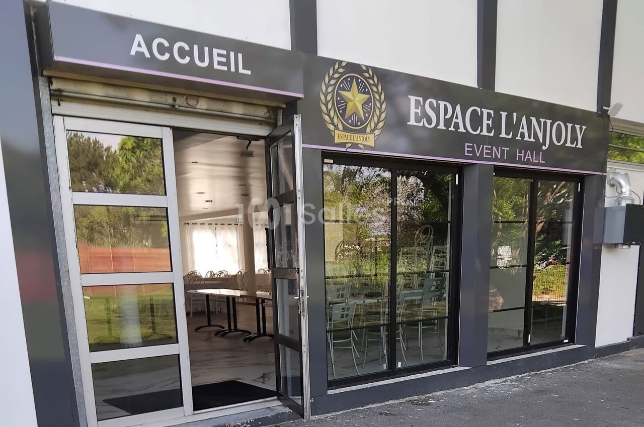 Façade vitrée d'une salle événementielle avec enseigne ’Espace L'Anjoly’ et entrée indiquée par ’Accueil’.