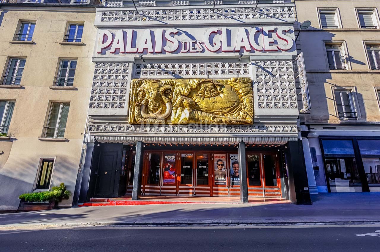 Façade du théâtre Palais des Glaces à Paris, avec une sculpture dorée et des affiches visibles sur les vitrines.