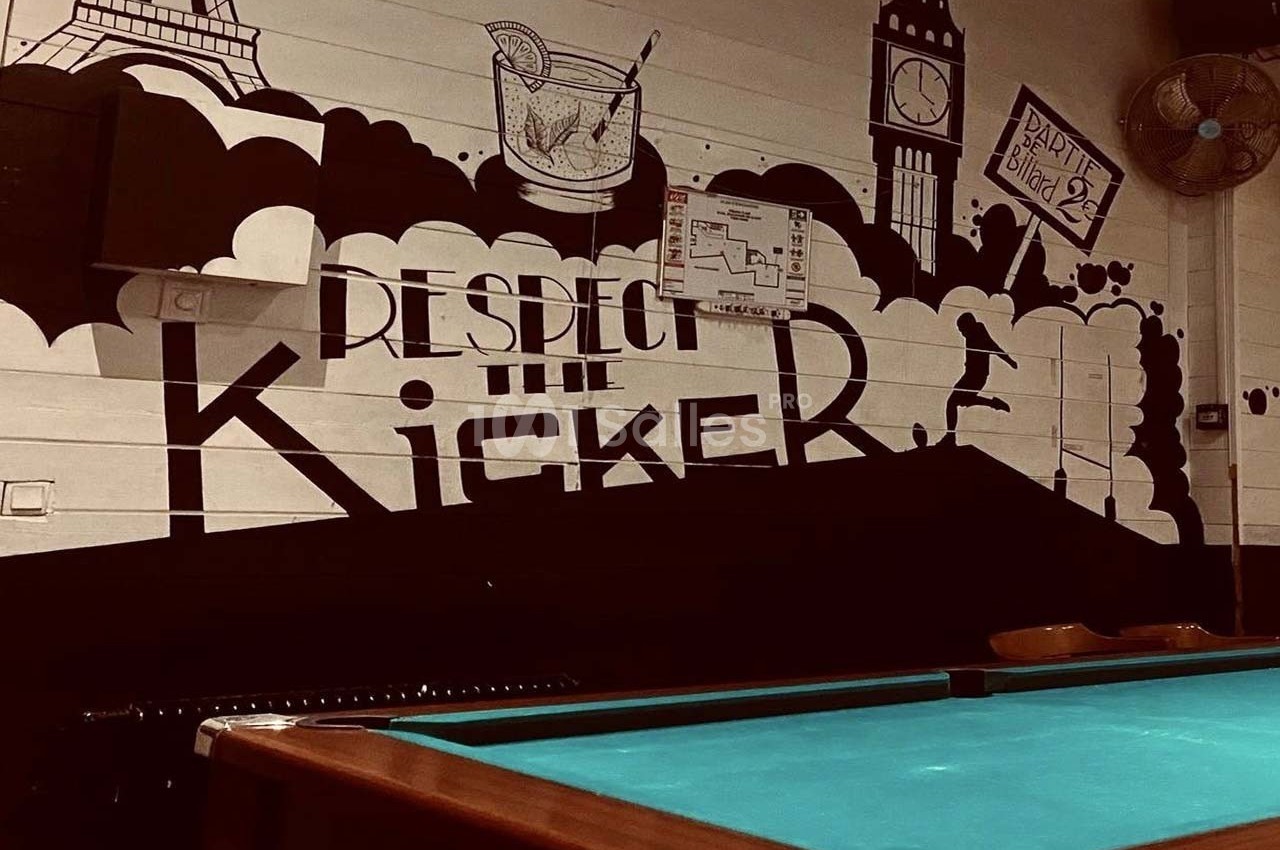 Mur décoré avec des illustrations de monuments, un cocktail et une table de billard au premier plan.