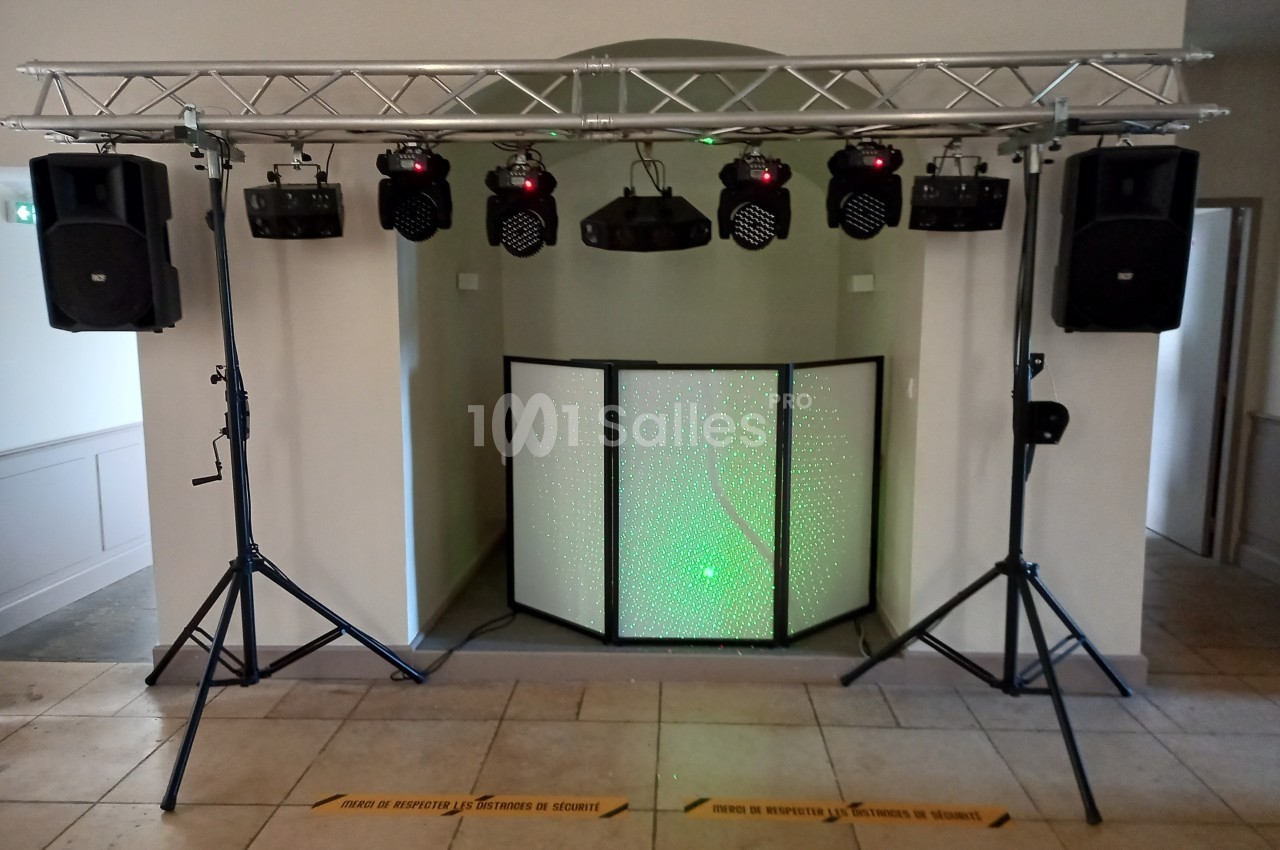 Installation de matériel de sonorisation et d'éclairage avec projecteurs, enceintes et écran lumineux dans une salle.
