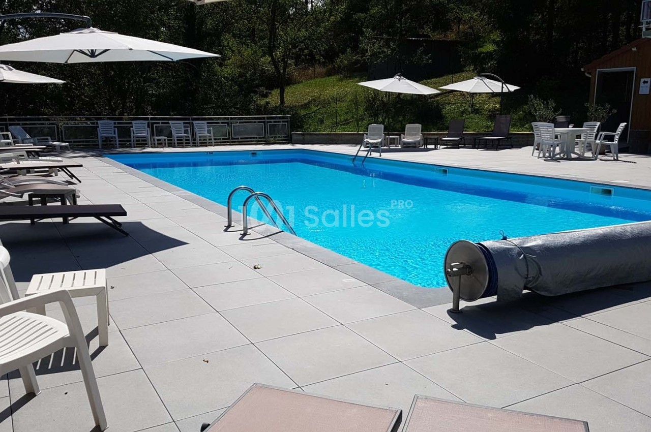 Piscine extérieure avec parasols, chaises longues et mobilier de jardin sur une terrasse ensoleillée.
