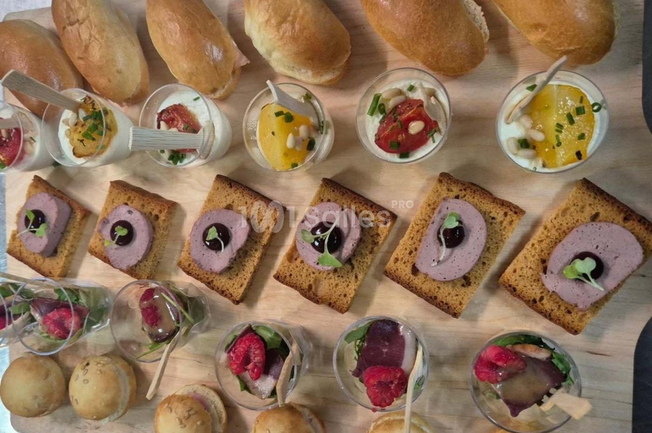 Assortiment de verrines, toasts et pains variés disposés sur une planche en bois.