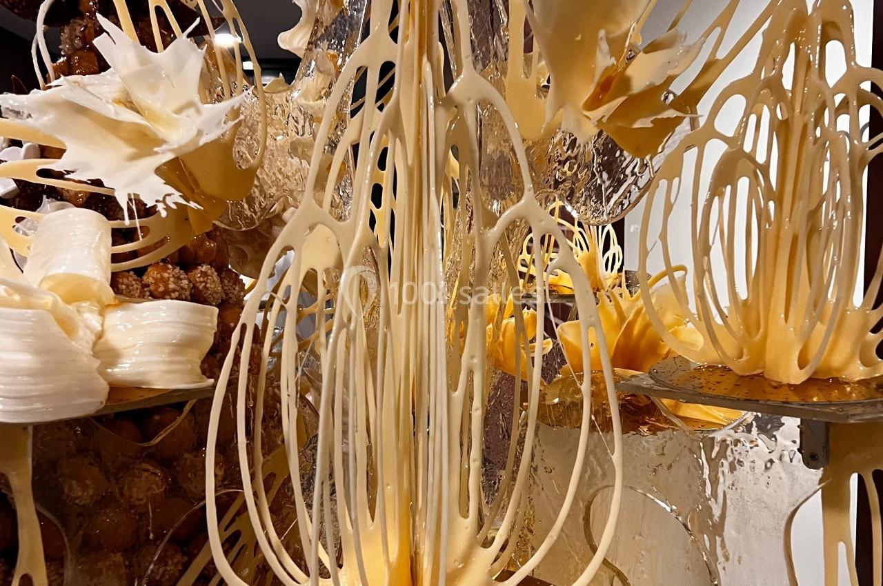Structure artistique complexe en sucre filé et caramel, composée de formes organiques et translucides.
