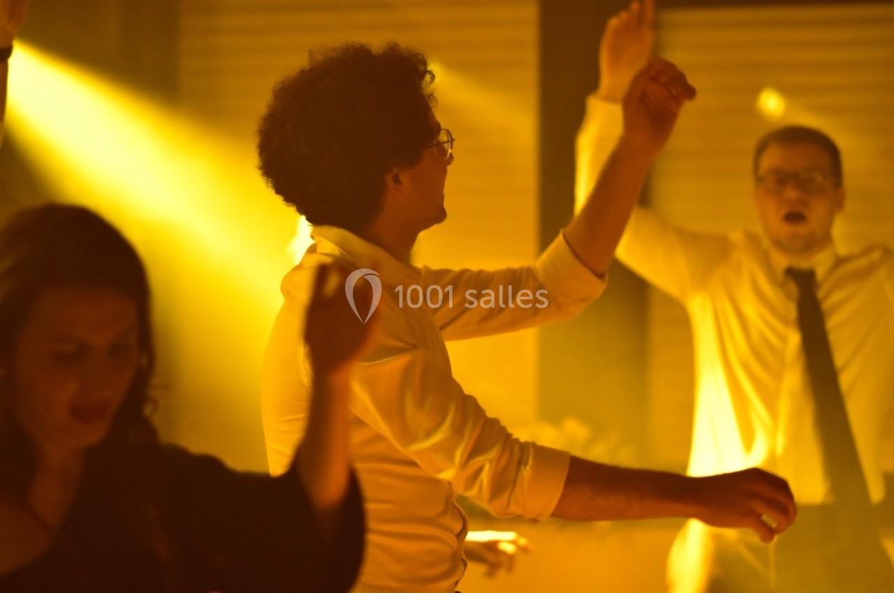 Des personnes dansent dans une ambiance tamisée avec une lumière jaune dominante.