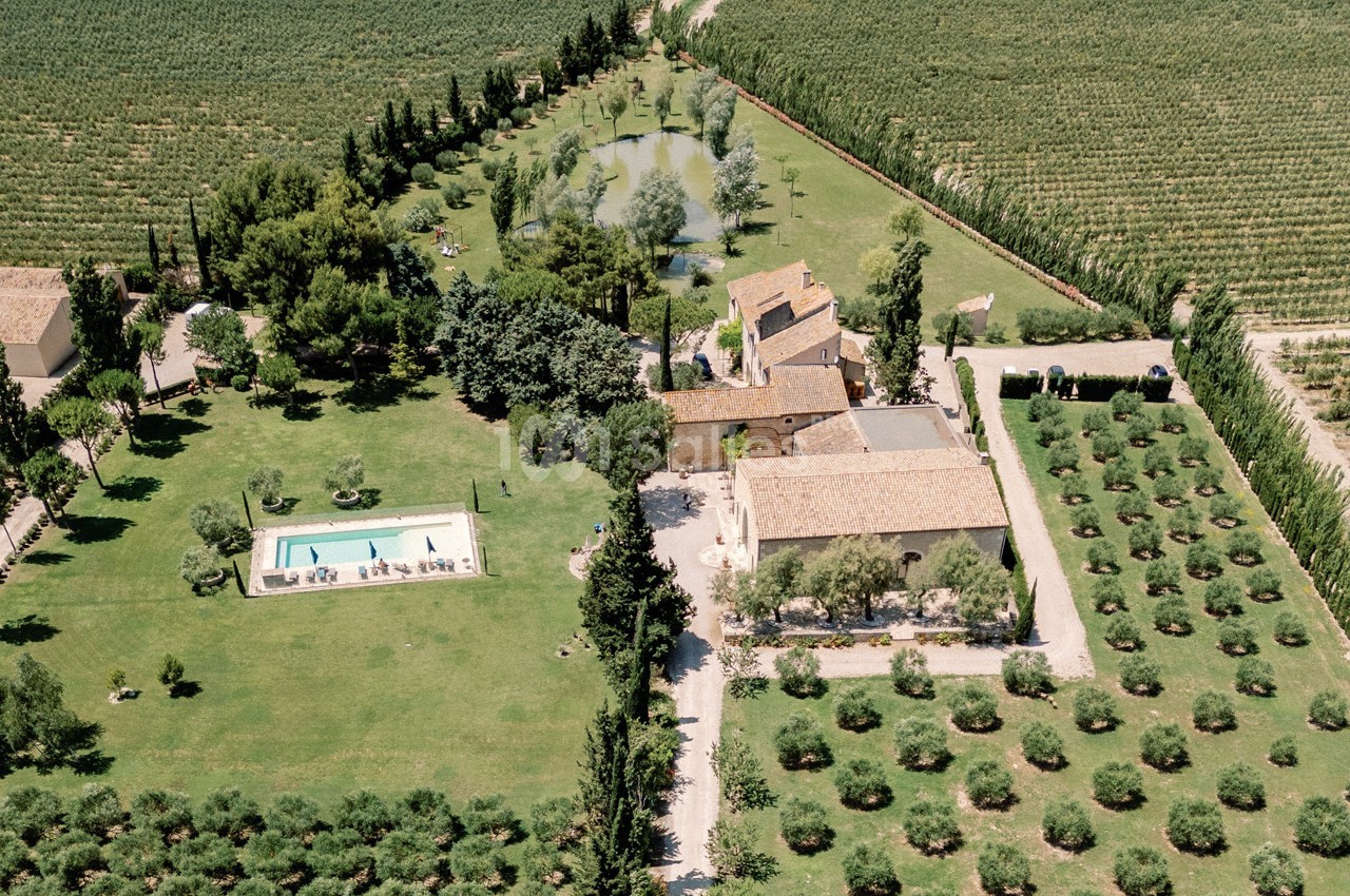 Vue aérienne d'une propriété rurale avec piscine, bâtiments en pierre, jardins et champs environnants.