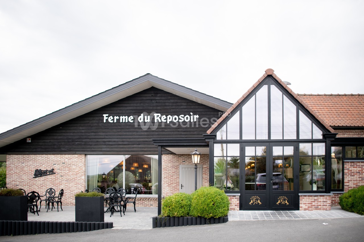 Façade d'un restaurant en briques et bois avec terrasse extérieure et grandes baies vitrées.