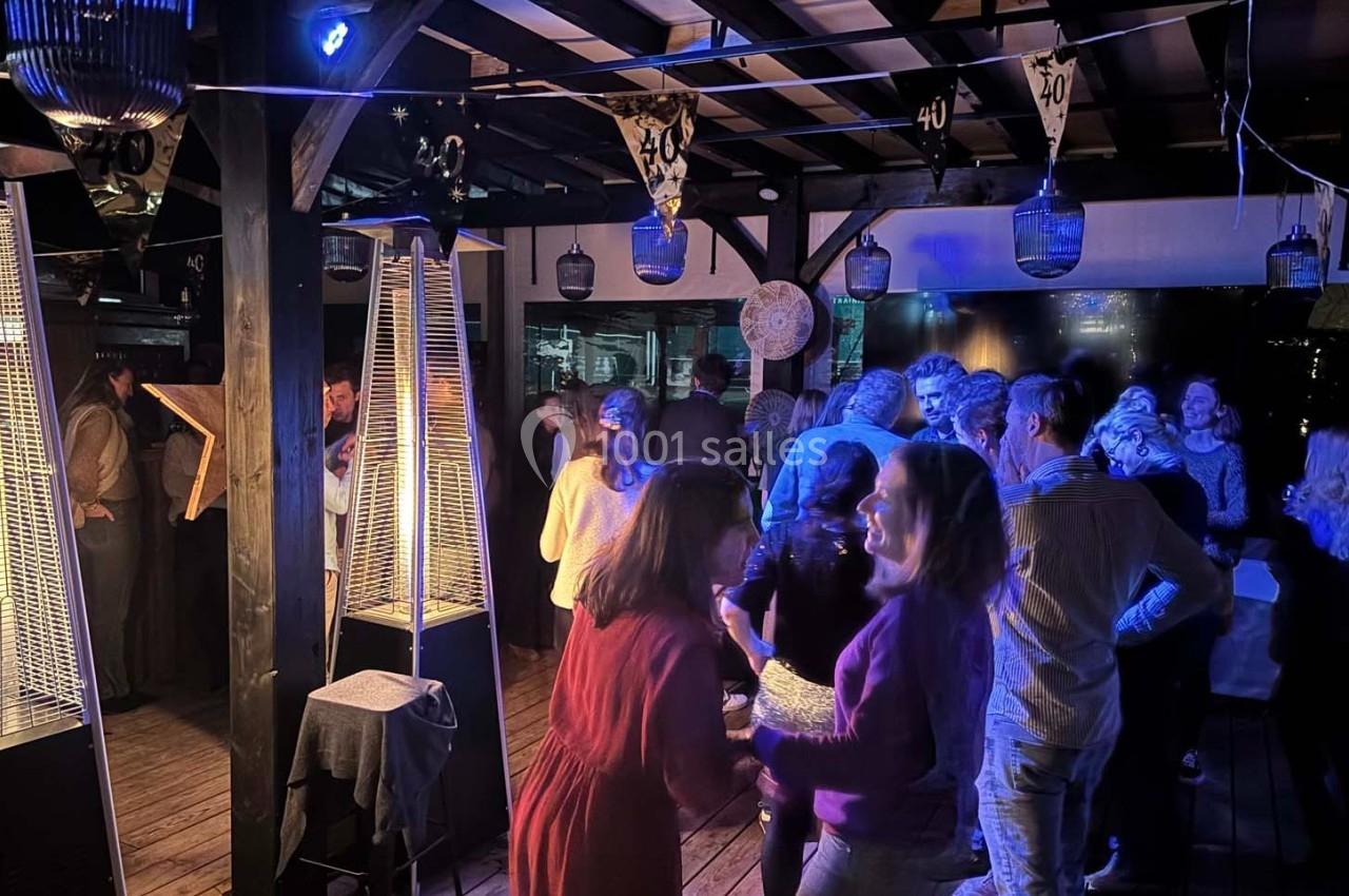 Groupe de personnes discutant et dansant lors d'une fête nocturne sous une pergola éclairée.