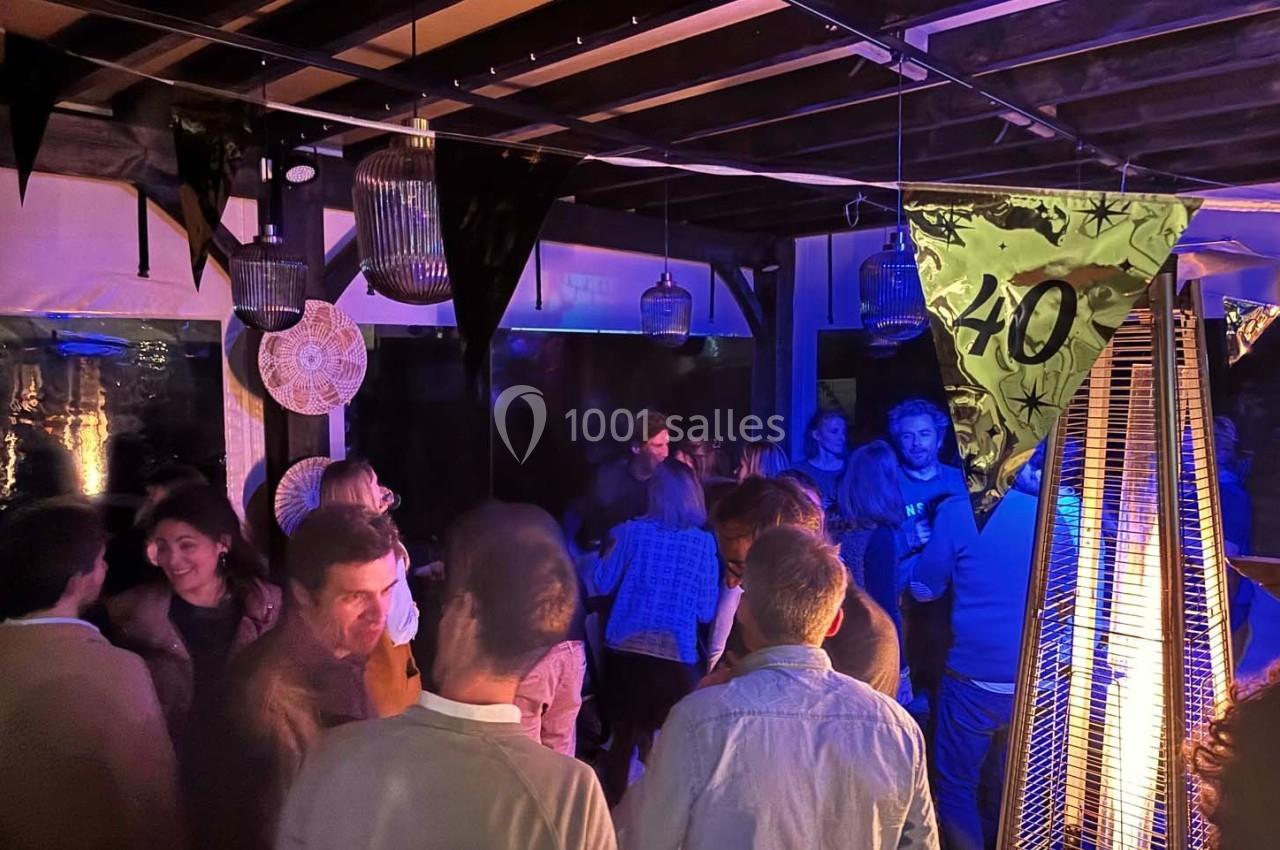 Personnes rassemblées dans un espace couvert, éclairé par des lumières tamisées et une décoration marquant un 40e…