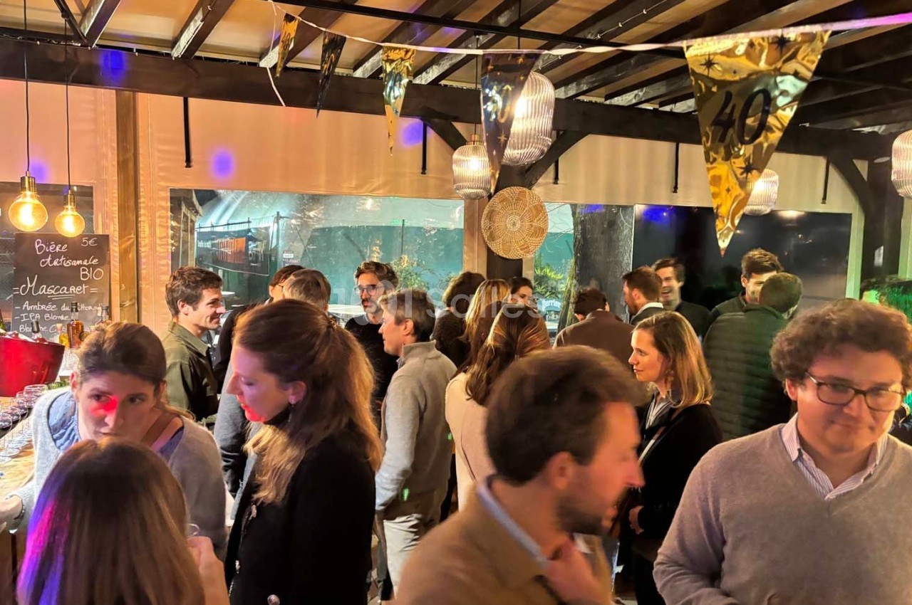 Groupe de personnes discutant lors d'une soirée conviviale dans un espace décoré avec des guirlandes et des lumières.