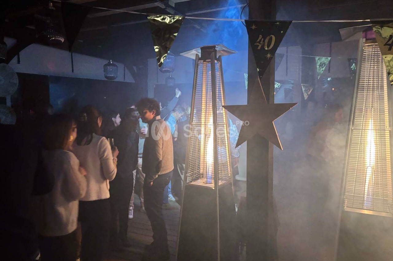 Personnes rassemblées dans une ambiance festive avec des chauffages extérieurs et des décorations pour un 40e anniversaire.