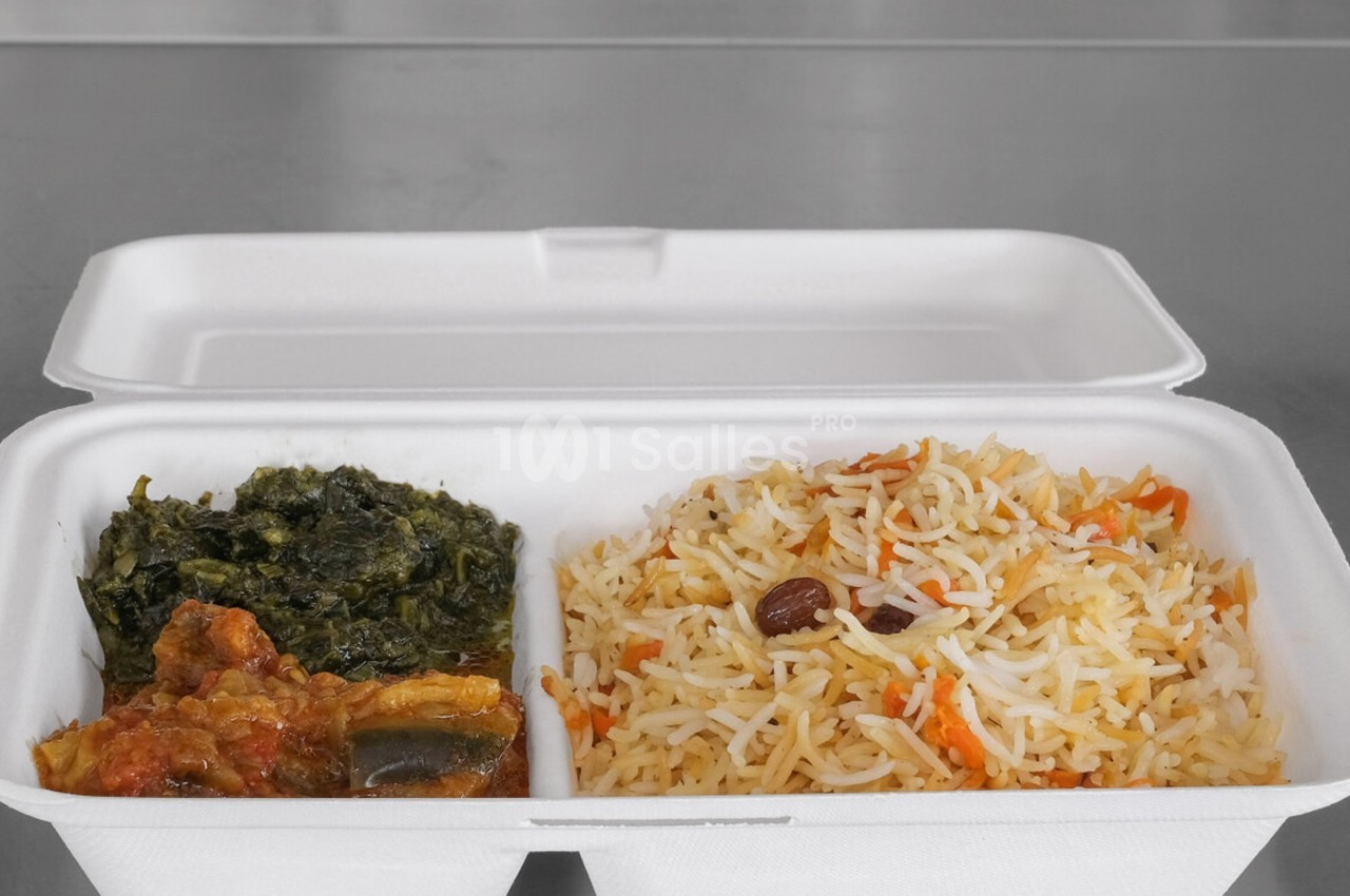 Plat à emporter dans une boîte en carton contenant du riz basmati aux légumes, des épinards et un ragoût de viande.