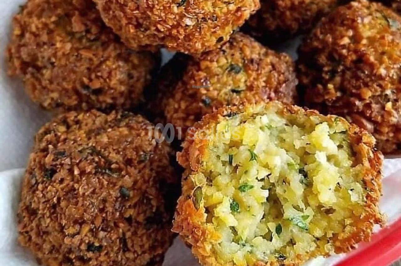 Boulettes de falafel dorées, dont une coupée en deux révélant une texture moelleuse et des herbes à l'intérieur.
