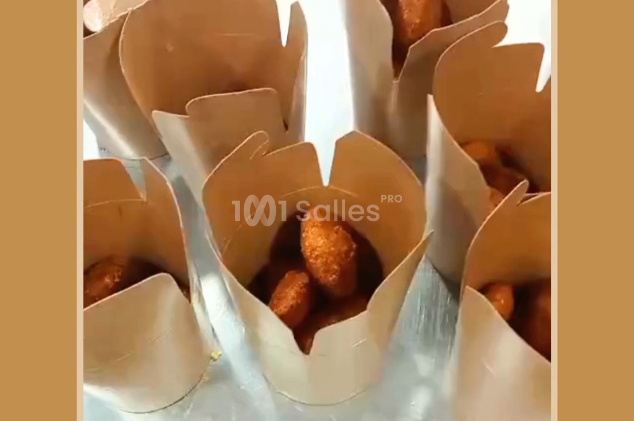 Croquettes dorées servies dans des contenants en carton brun disposés sur une surface métallique.