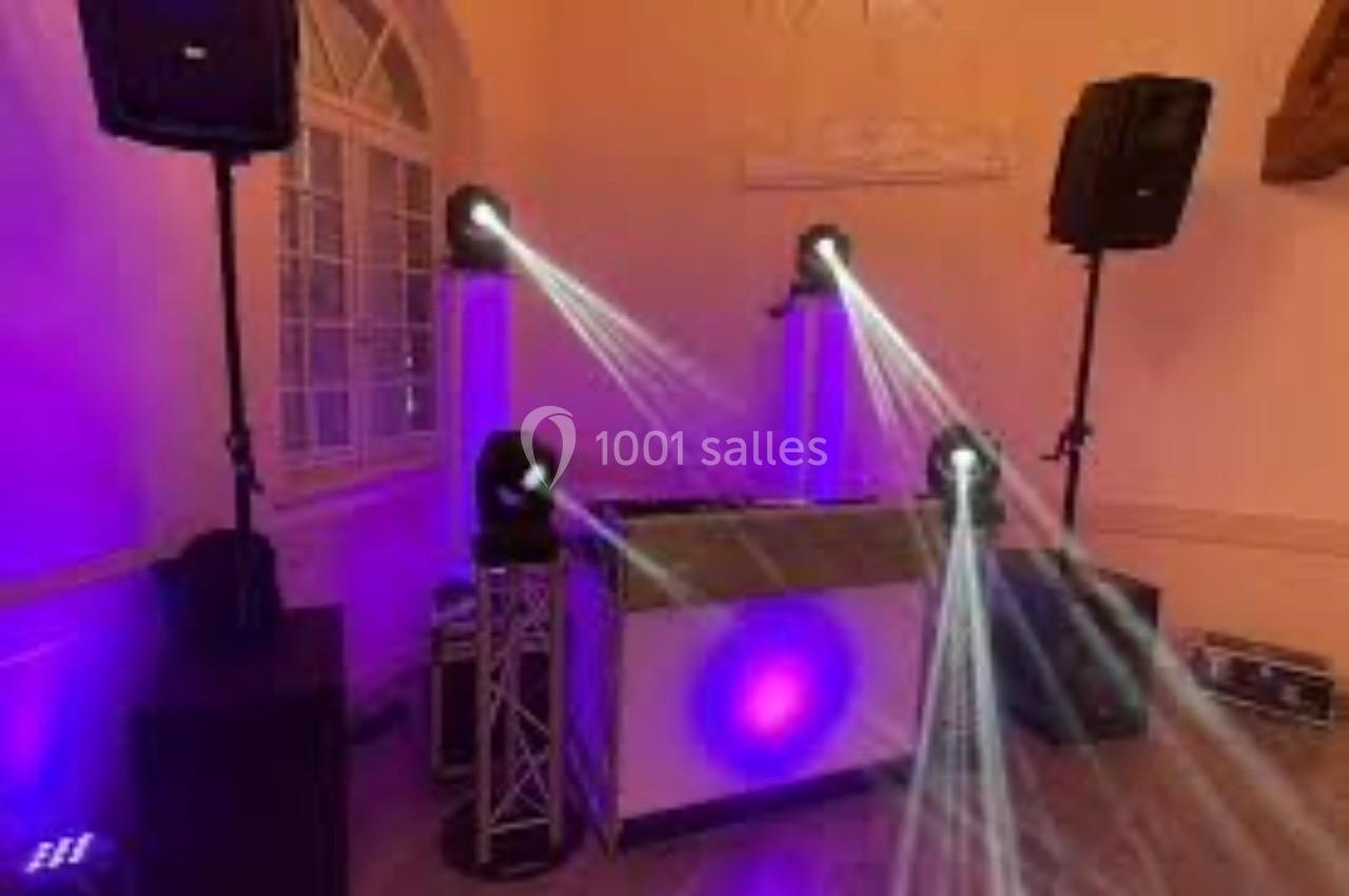 Installation de matériel de sonorisation et éclairage avec projecteurs lumineux dans une salle aux murs clairs.