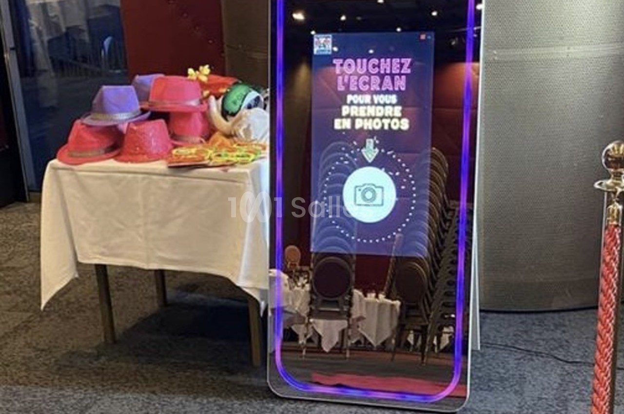 Miroir interactif avec instructions pour prendre une photo, à côté d'une table avec accessoires colorés.