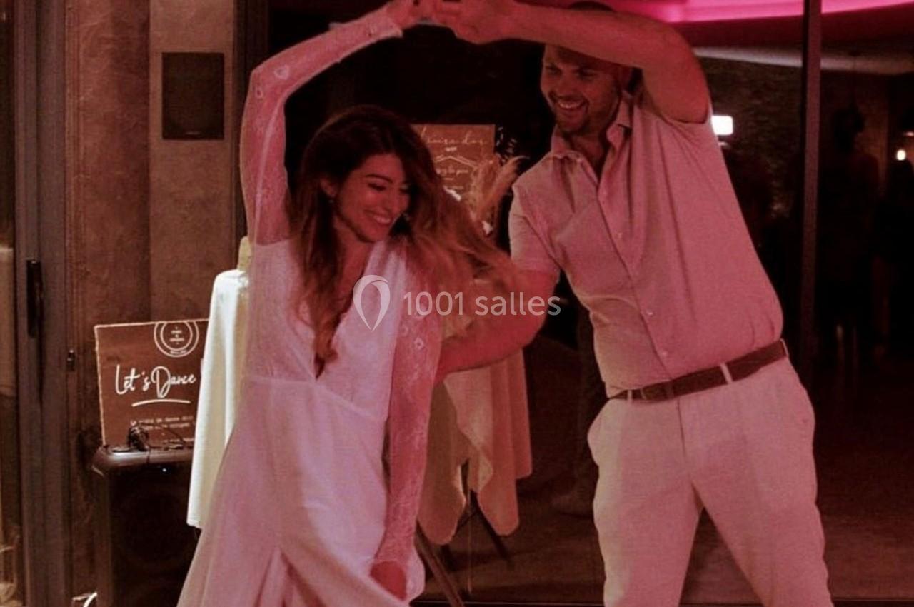 Un couple danse joyeusement dans une ambiance tamisée avec des lumières rouges en arrière-plan.