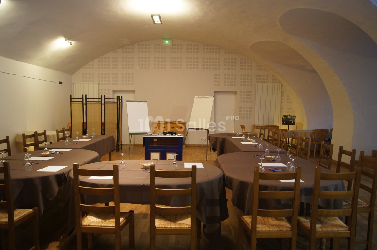 Salle de réunion avec tables ovales, chaises en bois, paperboards et matériel de présentation.