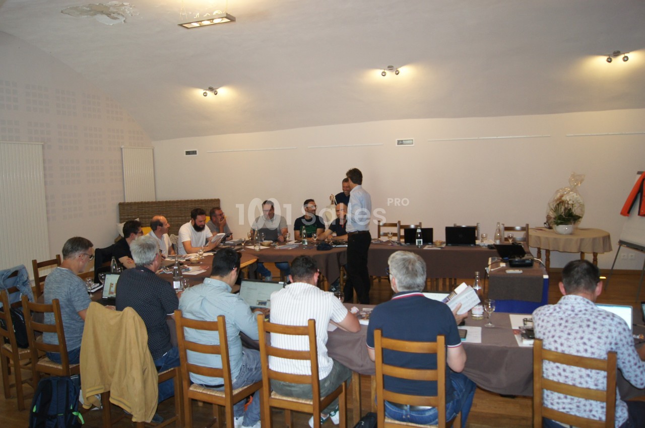 Un groupe de personnes assises autour d'une table en réunion dans une salle éclairée.