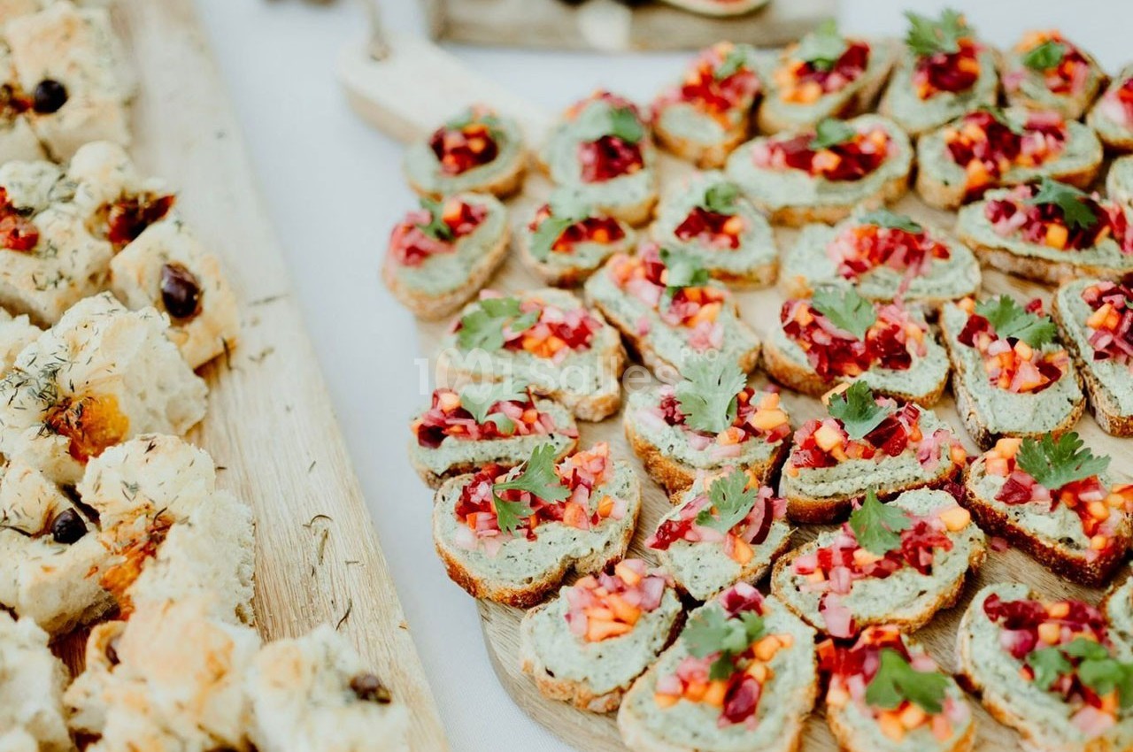 Plateau de toasts garnis de légumes colorés et herbes fraîches, disposés sur une table en bois.