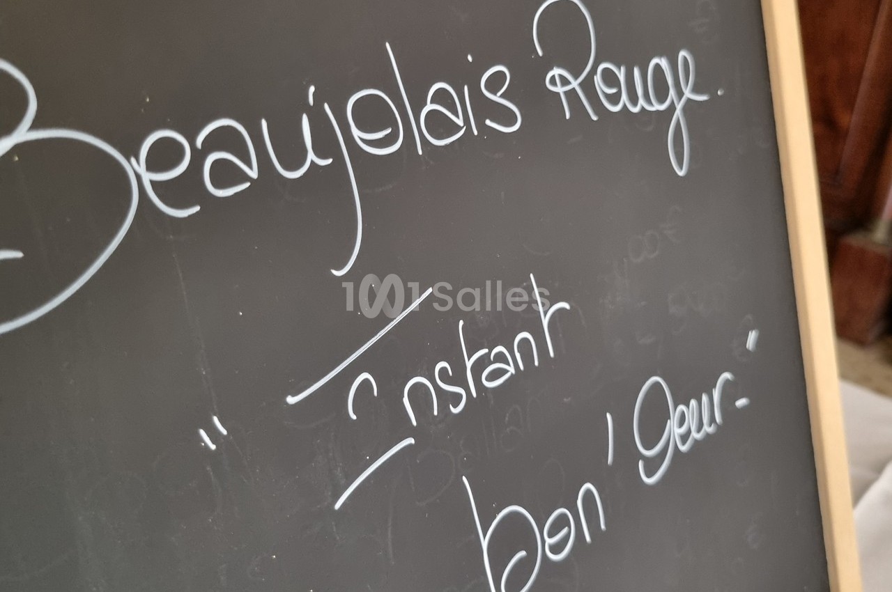 Ardoise avec l'inscription manuscrite ’Beaujolais Rouge’ et ’Instant bon'heur’ en lettres blanches.