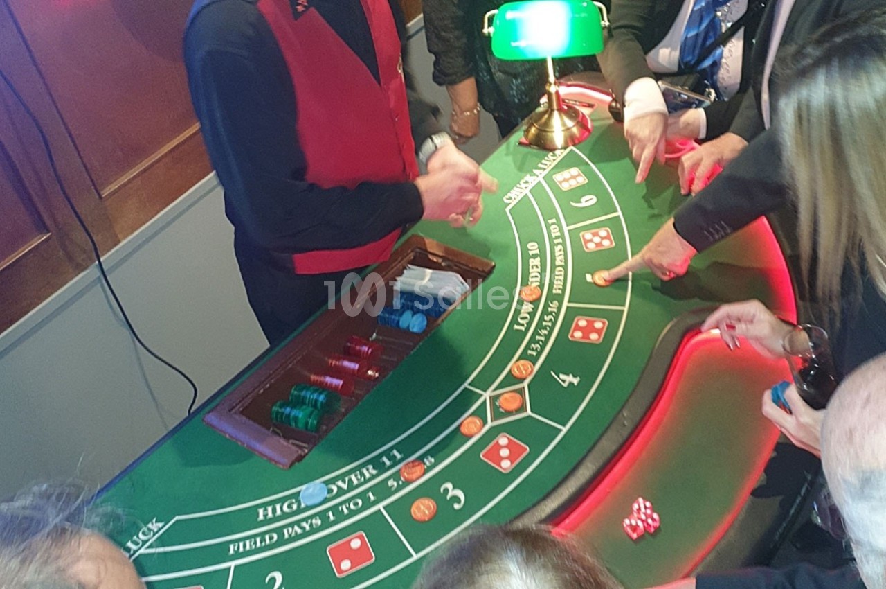 Croupier animant une table de craps avec des joueurs pointant vers les dés et les cases de pari.