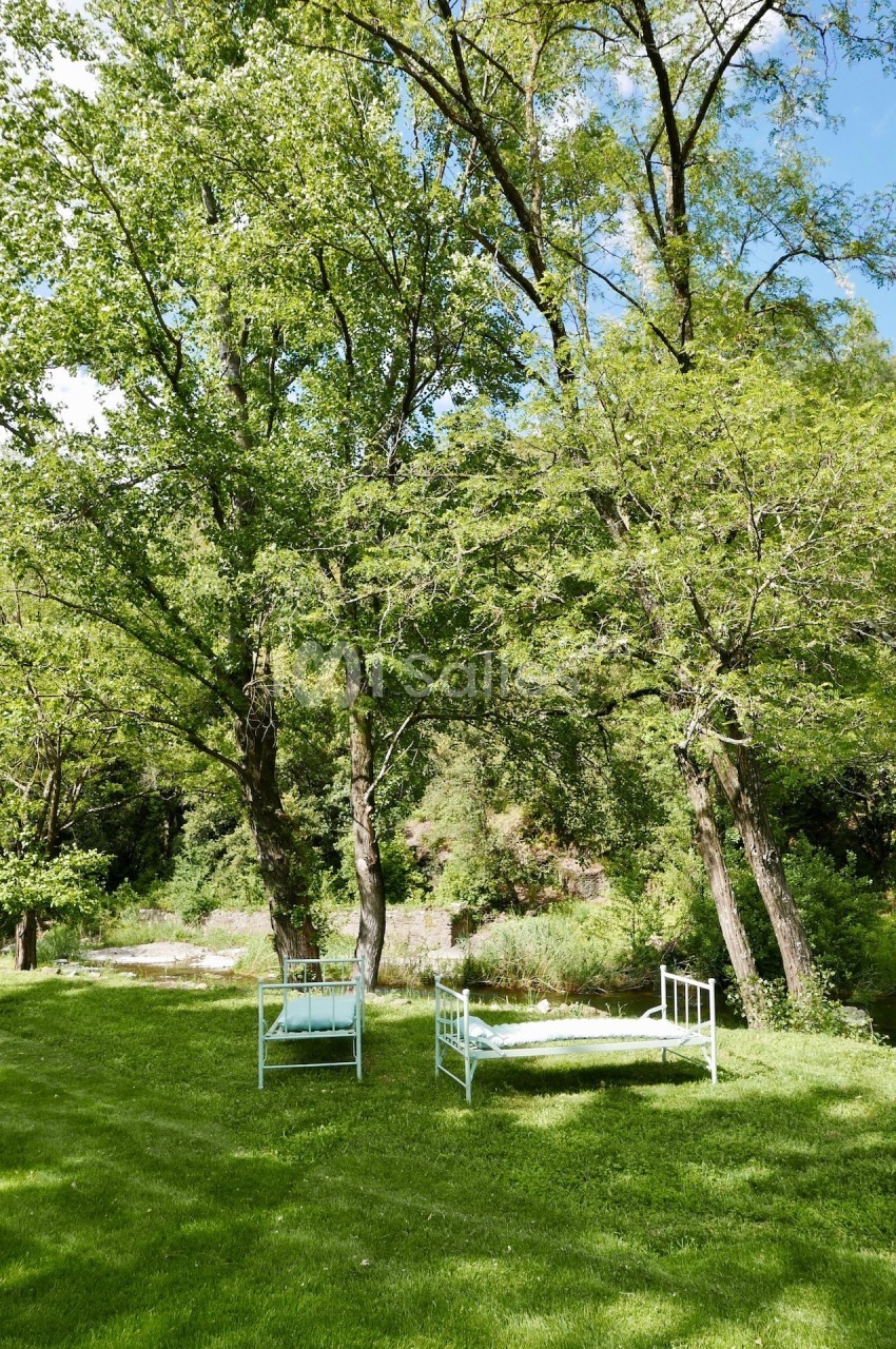 Deux lits de jardin blancs placés sur une pelouse verte, entourés d'arbres et d'un paysage naturel.