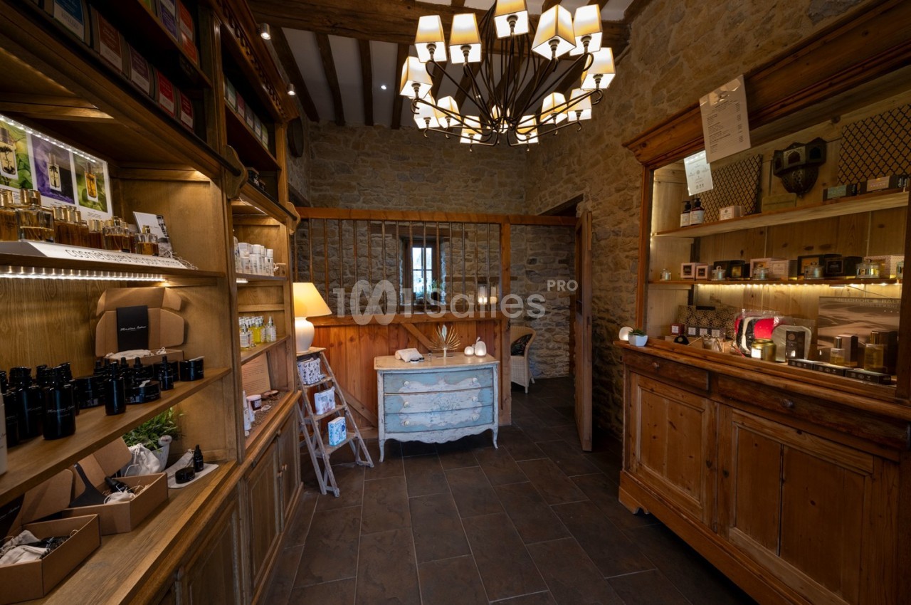 Boutique rustique avec étagères en bois exposant des produits, éclairée par des lampes suspendues et une lumière chaleureuse.