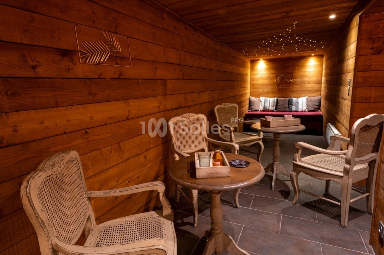 Salon chaleureux en bois avec fauteuils en osier, tables basses et éclairage tamisé créant une ambiance cosy.