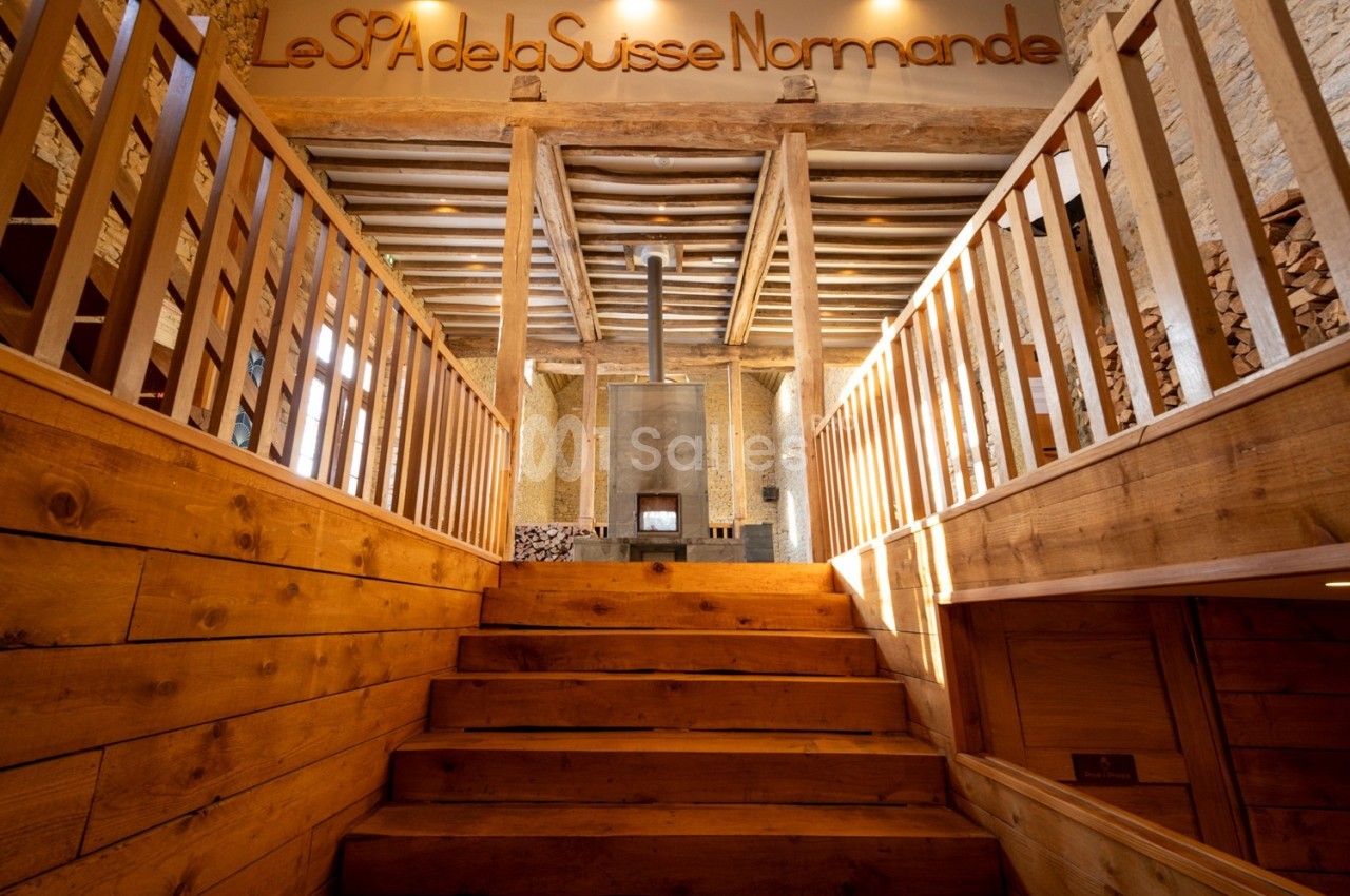 Escalier en bois menant à une entrée de spa avec des murs en pierre et une ambiance chaleureuse.