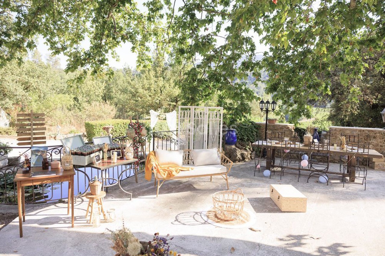 Espace extérieur aménagé avec des meubles et décorations, sous des arbres offrant de l'ombre par une journée ensoleillée.