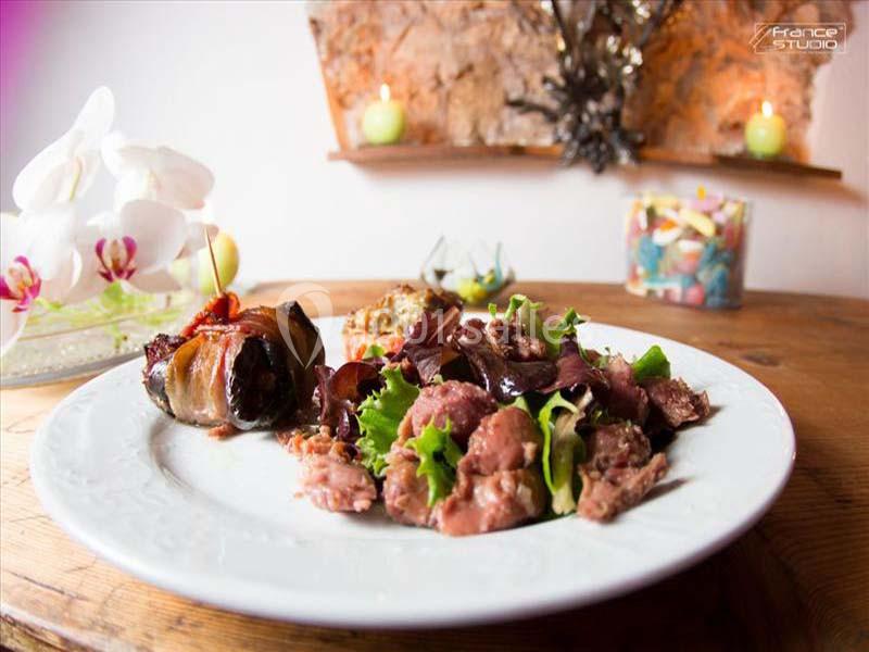 Assiette garnie de salade, viande et accompagnements, présentée sur une table en bois avec une décoration en arrière-plan.