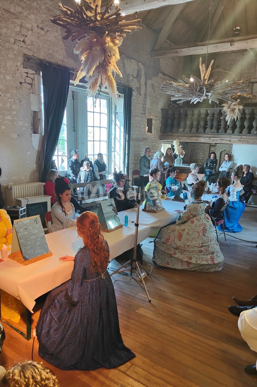 Des personnes en costumes d'époque participent à une activité autour de tables dans une salle au décor ancien.