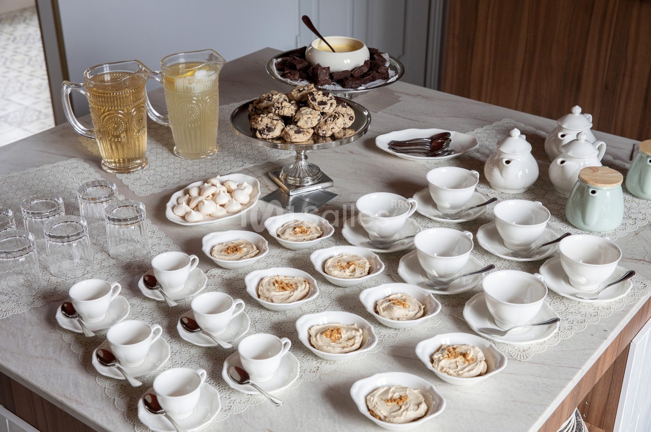 Table dressée avec des tasses, assiettes de desserts, pichets de boissons, théières et plateaux de biscuits.