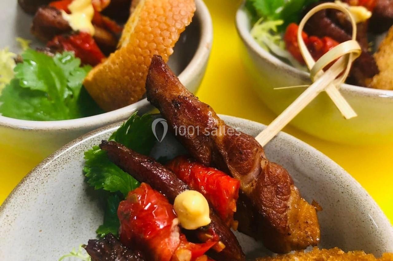 Brochettes de viande et légumes grillés servies avec des tranches de pain et des herbes fraîches dans des bols individuels.