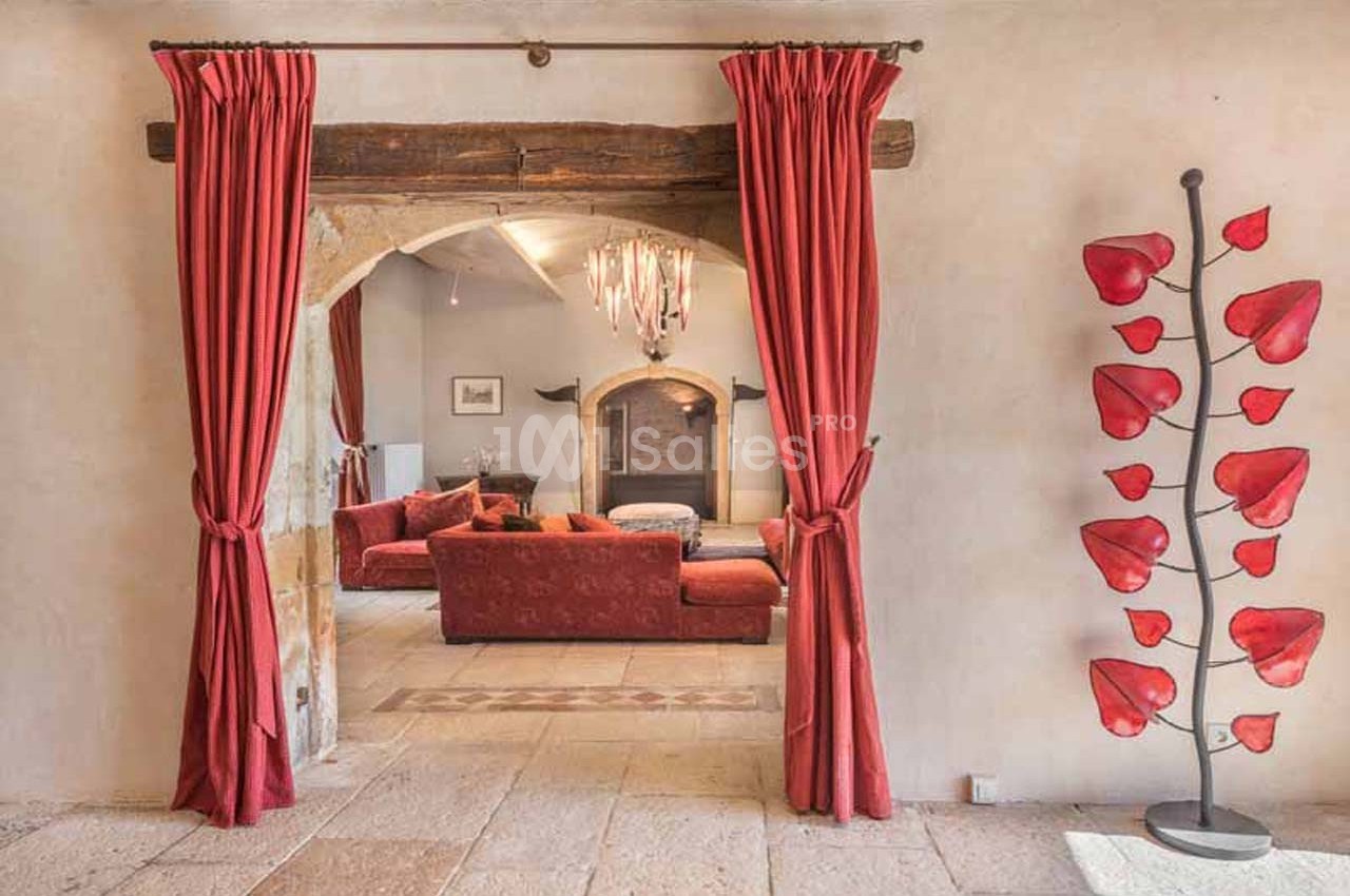 Vue d'un salon chaleureux avec canapé rouge, cheminée, rideaux assortis et sculpture décorative en forme de feuilles rouges.
