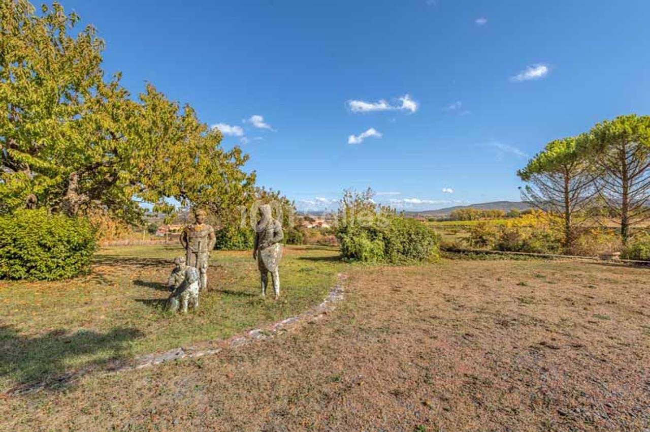 Statues représentant deux figures humaines et un chien dans un parc avec arbres et ciel dégagé en arrière-plan.
